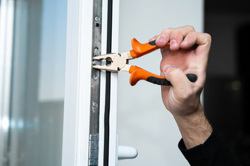 Professional master for repair and installation of windows, sets up a window opening system in winter mode