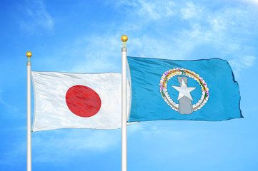 Japan and Northern Mariana Islands two flags on flagpoles and blue cloudy sky