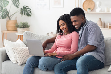 Obraz premium Quarantine Leisure Concept. Happy Black Couple Relaxing With Laptop At Home