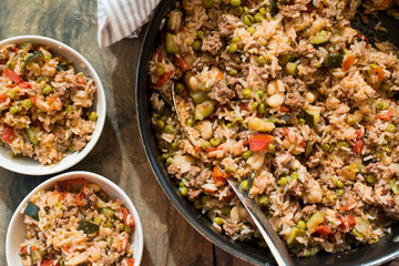 A casserole with rice and tomatoes and beans made in a copper pot and served in white dishes for a healthy meal