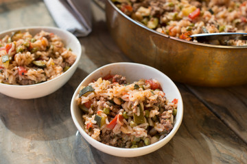 A casserole with rice and tomatoes and beans made in a copper pot and served in white dishes for a healthy meal
