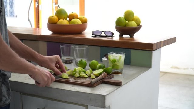 Close up of man hand preparing recipe for &ldquo;caipirinha&rdquo; drink with lime, sugar, ice and &ldquo;cachaca&rdquo; on kitchen countertop. The cacha&ccedil;a of Brazil is made of sugar cane. 4K