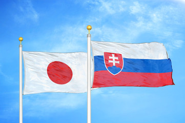 Japan and Slovakia two flags on flagpoles and blue cloudy sky