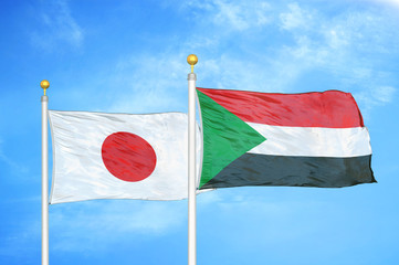 Japan and Sudan two flags on flagpoles and blue cloudy sky