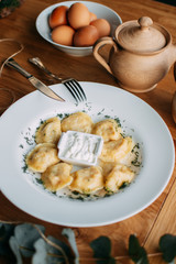 Meat Dumplings - russian pelmeni with sour cream on rustic background