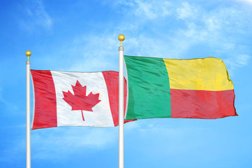 Canada and Benin  two flags on flagpoles and blue cloudy sky