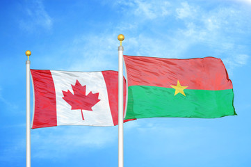 Canada and Burkina Faso  two flags on flagpoles and blue cloudy sky