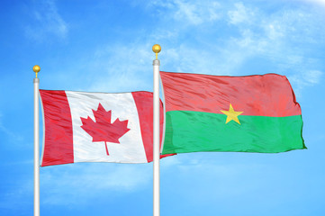 Canada and Burkina Faso  two flags on flagpoles and blue cloudy sky