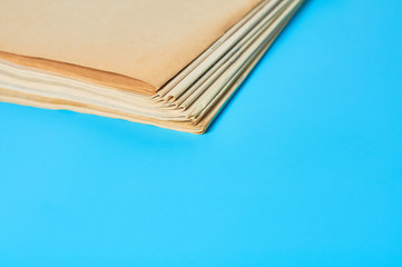 Heap of blank magazines, newspapers on blue background. Concept of workspace of journalist