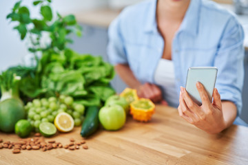 Healthy adult woman with green food in the kitchen