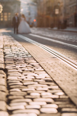 tram tracks and pavement in the foreground. newlyweds are walkin