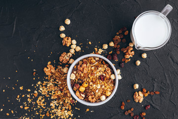 large serving of nutritious granules with nuts and dried fruits on a black stone background with place for your text