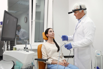 Obraz premium Doctor examining patient with modern equipment before nasal surgery in clinic