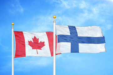 Canada and Finland two flags on flagpoles and blue cloudy sky