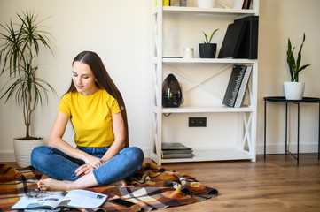 Young attractive girl reads magazines at home