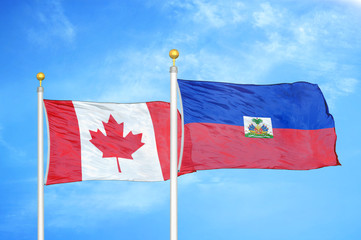 Canada and Haiti two flags on flagpoles and blue cloudy sky
