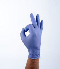 Right hand in blue glove, fingers in the shape OK