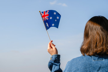 Woman hand with Australian swaying flag on the blue sky. Australia. Concept