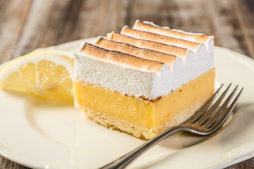 portion of lemon cake on plate on wood