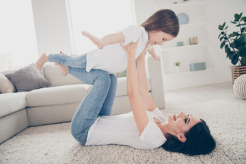 Fototapeta na wymiar Full length photo of cheerful cute adorable mommy lay carpet hold her small kid imagine she fly like bird in living room apartment house indoors