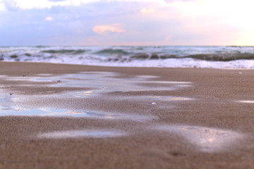 Mirror image of the sunset on a wet sandy beach. Copy space for background