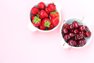 Ripe berries - strawberries and cherries in a plate. Still life with strawberries and cherries on pink background.