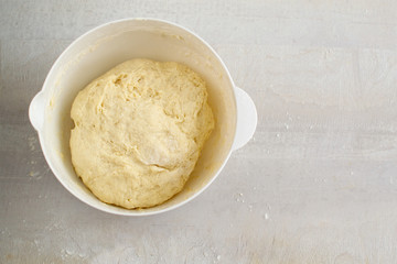 Raw dough in a white plastic plate on the table. Preparation for cooking. Top view