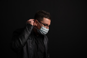 portrait of brunette man in a surgical bandage on a background of a modern building, coronavirus, illness, infection, quarantine, medical mask