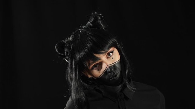 a girl with black hair in an art image on a black background poses moving in front of the camera while a slow motion.