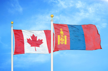 Canada and Mongolia two flags on flagpoles and blue cloudy sky