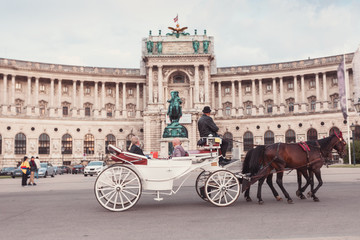 Fototapeta premium Hofburg Palace and Heldenplatz with a passing carriage with a pair of horses, Vienna, Austria