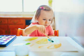 Girl drawing rainbow with colorful aquarelle paints