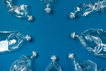 A lot of used plastic bottles on a blue background. The concept of pollution of the planet and the oceans with plastic waste. copy space.