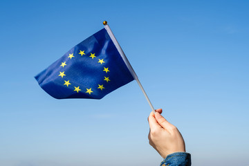Woman hand with EU(European) swaying flag on the blue sky. Europe. Concept - obrazy, fototapety, plakaty