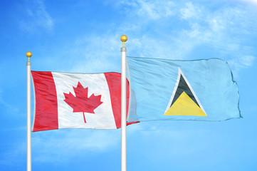 Canada and Saint Lucia two flags on flagpoles and blue cloudy sky