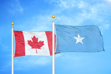 Canada and Somalia two flags on flagpoles and blue cloudy sky