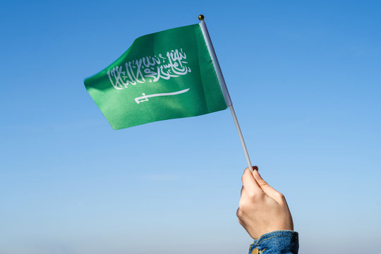 Muslim woman with Saudi Arabia flag on the blue sky. Concept