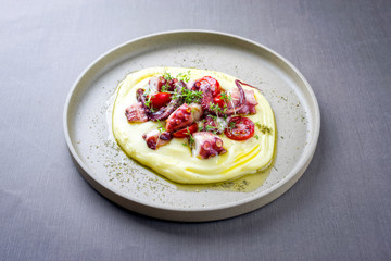 Traditioneller italienischer Oktopus polpo alla griglia mit Kartoffel Püree Creme und Tomaten als closeup auf einem Modern Design Teller © HLPhoto