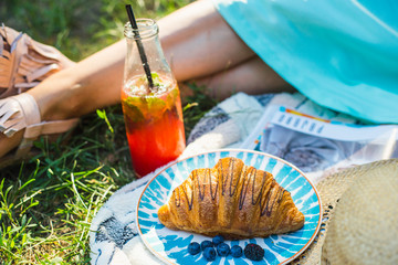 closeup of croissant on blue plate. still life with croissant. home garden picnic during isolation quarantine. croissant and blueberries in garden. picnic at home. picnic decoration. 