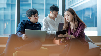 Business meeting and teamwork concept. Asian businesswoman explaining project data report to colleagues using digital tablet for presentation at workplace. Coworkers team brainstorming ideas in office