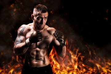 Mixed martial artist posing against the backdrop of fire and smoke. Concept of mma, ufc, thai...