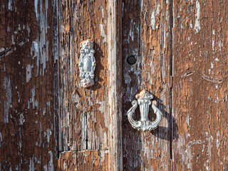 Detalle de una puerta de madera vieja con un llamador y una cerradura