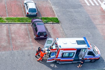 Top view of paramedic team moving man on ambulance stretcher into car  © yaalan