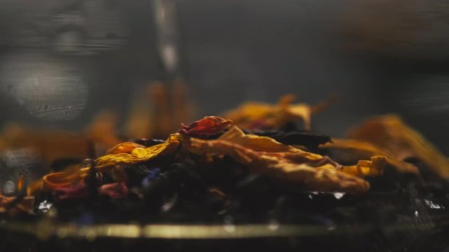 Tea ceremony. Dry leaf tea with additives fills with hot water. A close-up.