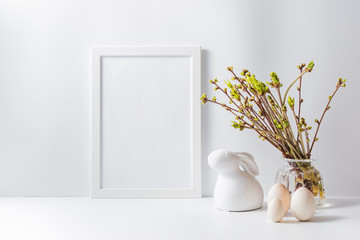 Home interior with easter decor. Mockup with a white frame and green buds on branches in a vase on a light background