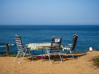 Una mesa y tres sillas de playa en un acantilado en Portugal