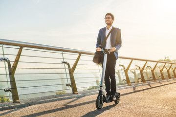 Ecological transportation concept. Young business man in suit riding electric scooter in office - Powered by Adobe