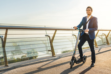 Young business man in suit riding an electric scooter on urban streets © InsideCreativeHouse