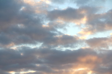 Fototapeta premium Clouds in the blue sky at sunset or dawn backlit by the sun. Place for text and design.