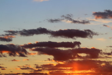 Clouds in the blue sky at sunset or dawn backlit by the sun. Place for text and design.